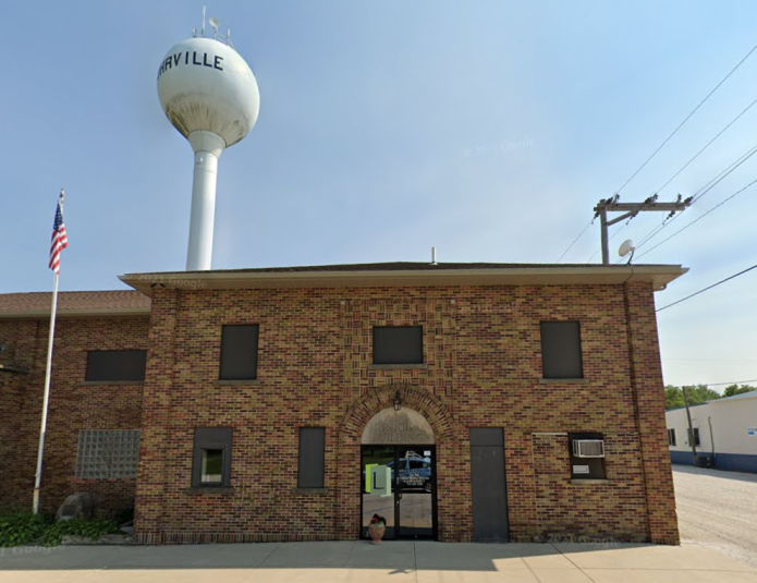 An exterior shot of the Lohrville, Iowa, Municipal Building, a brown brick two-story building. Behind the building is the water tower.